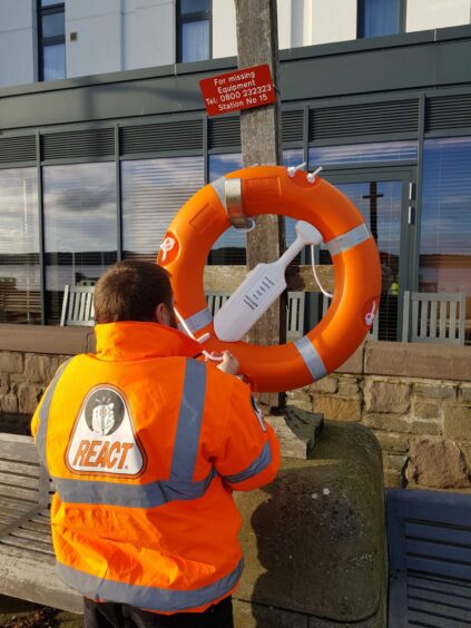 photo shows a volunteer in a high-vis jacket attaching a life ring to a post at Dundee's Riverside Drive.