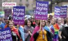 photo shows Pride marchers in Glasgow carrying placards saying 'Trans Rights Now'.