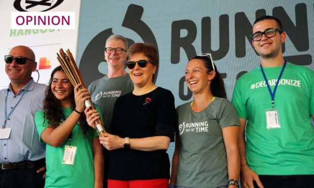 photo shows Nicola Sturgeon holding a baton at the end of the Running Out Of Time climate relay, at Cop27 in Egypt.