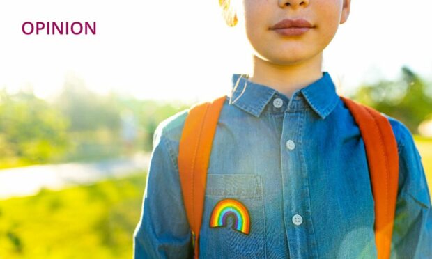 photo shows a child wearing a satchel and a blue denim shirt with a rainbow badge.