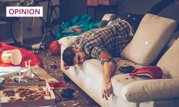 photo shows a young man passed out on his sofa with empty beer cans and a half-eaten pizza on the table in front of him.