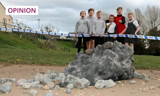 photo shows a lump of rock in the foreground with children pointing at it from behind police tape.