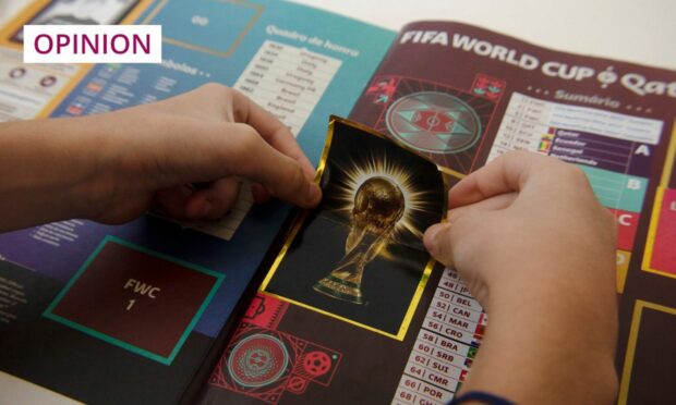 photo shows a pair of hands placing a sticker in a Panini World Cup 2022 album.