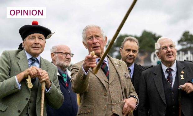 Photo shows King Charles at the Braemar highland games, talking to a group of men, some in traditional highland dresss.