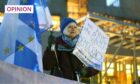 photo shows a woman with a Scotland/EU flag holding a placard which reads 'We hav the right to democracy'.