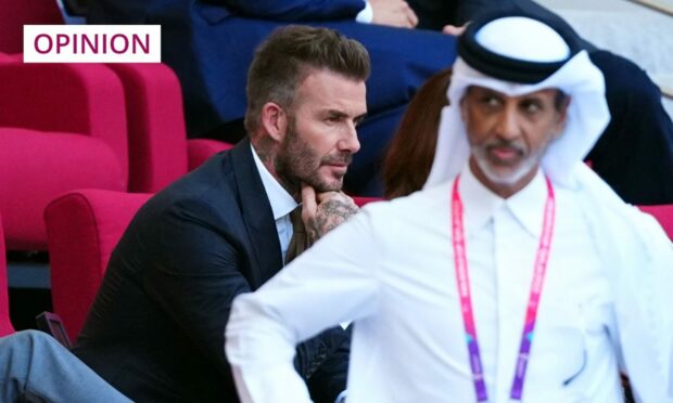 Photo shows David Beckham in the stands at a football stadium in Qatar.