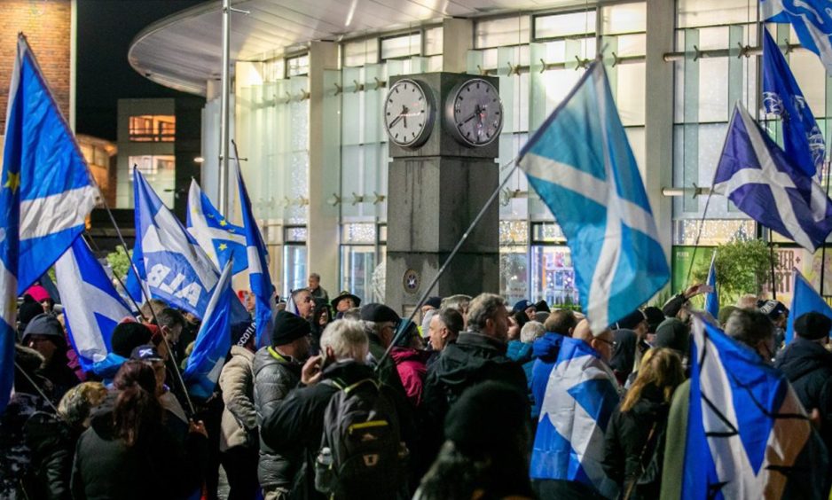 photo shows a large crowd of independence supporters waving saltires outside Perth Concert Hall.