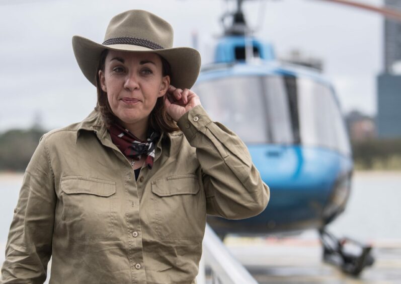 Photo shows Kezia Dugdale in khaki gear in front of a helicopter