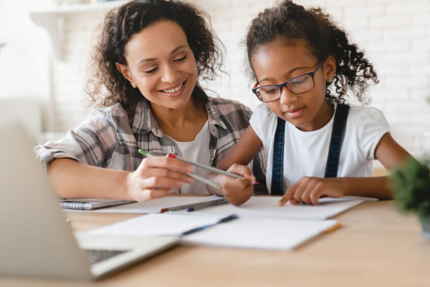 A woman tutoring a young girl. 