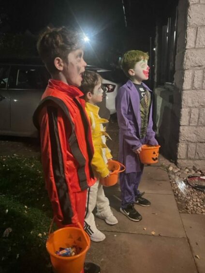 photo shows Martel's three sons standing on a doorstep in fancy dress with buckets full of sweets.