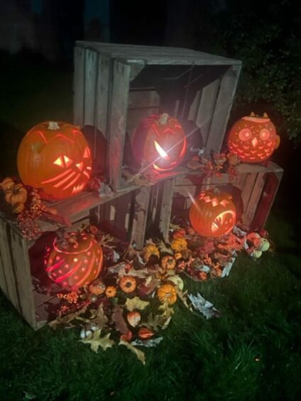 Photo shows a display of crates, filled with elaborately carved pumpkins.