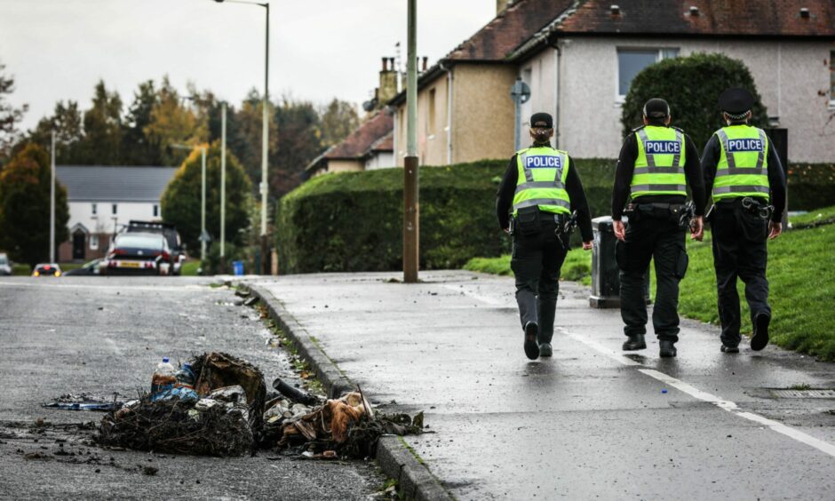 Police walk past burnt-out rubbish in Kirkton on Tuesday morning