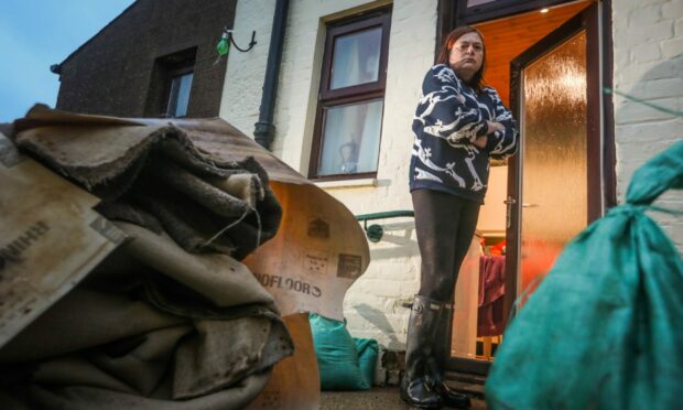 Kim Clark stands outside with the carpet and vinyl flooring she's had to rip up due to flooding. Image: Mhairi Edwards/DC Thomson