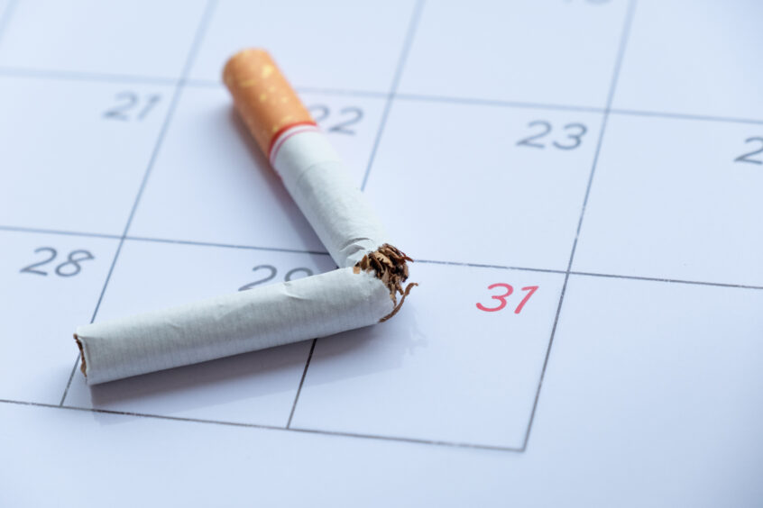 Broken cigarette resting on a calendar, image for the article on 'How can I stop smoking'.