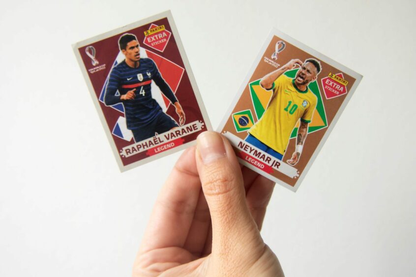 photo shows a hand holding two Panini stickers, featuring Raphael Varane and Neymar Jr.