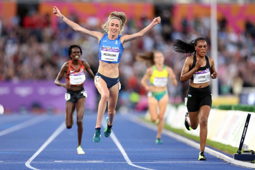 Eilish McColgan, arms in the air, as she crosses the finish line in the 10,000 metres race at the 2022 Commonwealth Games in Birmingham.