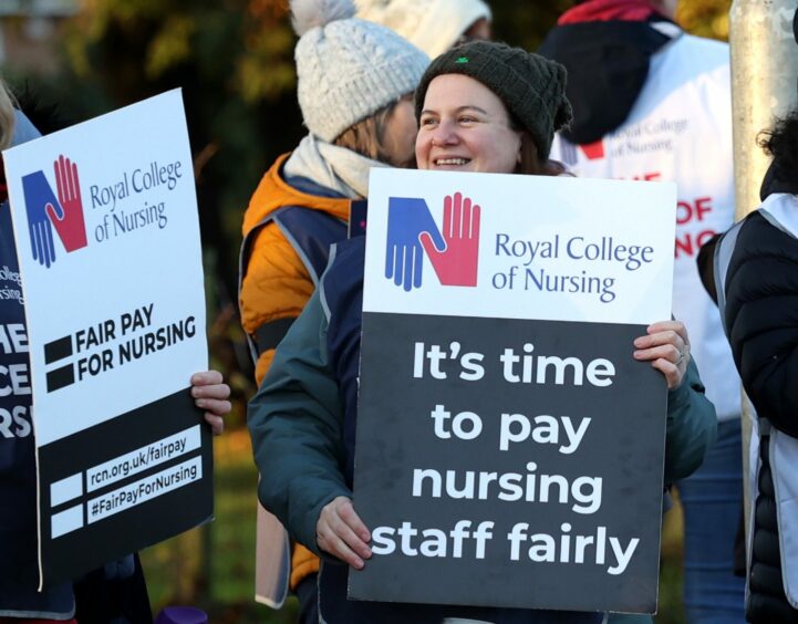 Woman on picket line holding a placard which reads: 'It's time to pay nursing staff fairly.'