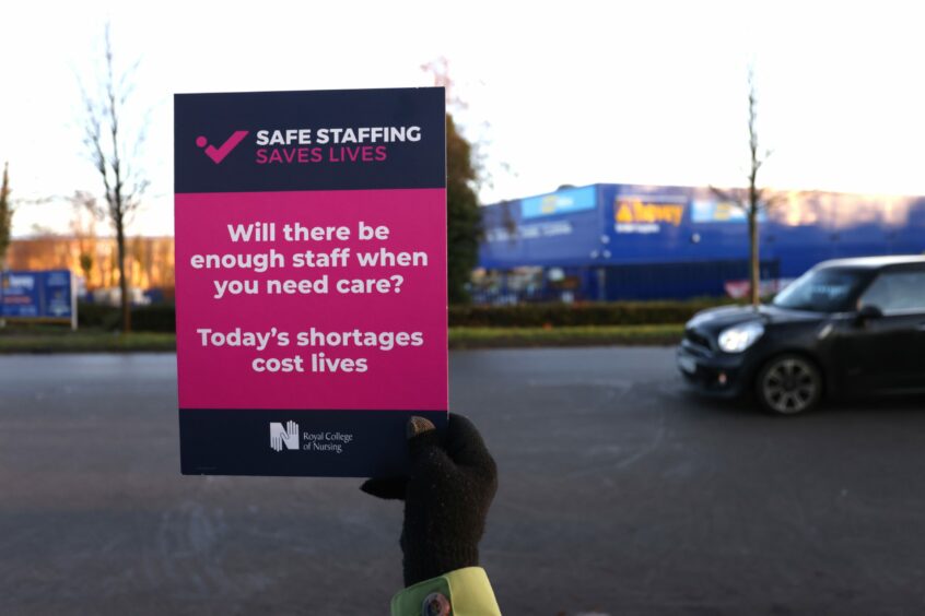 Hand holding a placard which reads: 'Will there be enough staff when you need care? Today's shortages cost lives'.
