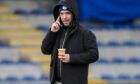 Morton manager Dougie Imrie speaks on the phone while holding a cup of tea. Image: SNS.