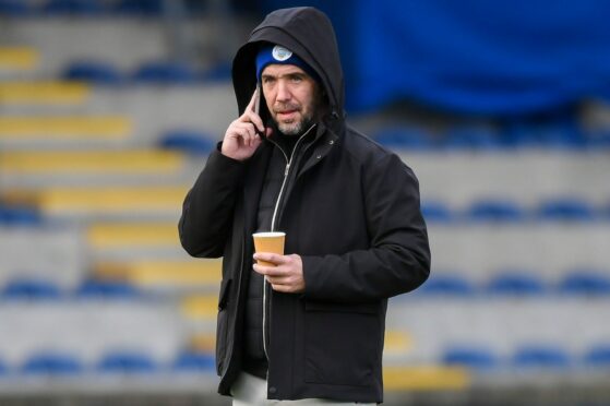 Morton manager Dougie Imrie speaks on the phone while holding a cup of tea. Image: SNS.