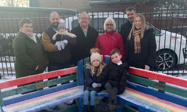 The buddy bench was gifted to Ancrum Road Primary in Dundee by the family of the late Euan Macdonald. Pictured from left are: Adrienne Heggie, partner of Euan's brother Chris Macdonald with baby Tanner, Ninian Macdonald, Euan's dad, Joan Macdonald, Euan's mum, David Macdonald, Euan's brother, Stacy Macdonald, David's wife, Jake and Lois. Image: Ancrum Road Primary School.