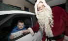 Jacob Bruce of Blairgowrie gets his present from Santa at Blairgowrie Fire Station.
Image: Phil Hannah.