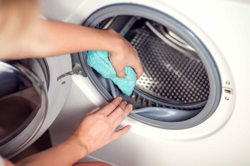 person wipes washing machine clean 