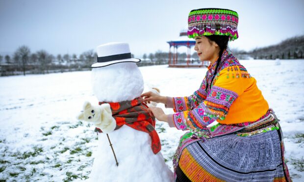 Student Norah decorates a snowman at Magdalen Green in Dundee in traditional Chinese clothing. Image: Blair Dingwall / DC Thomson