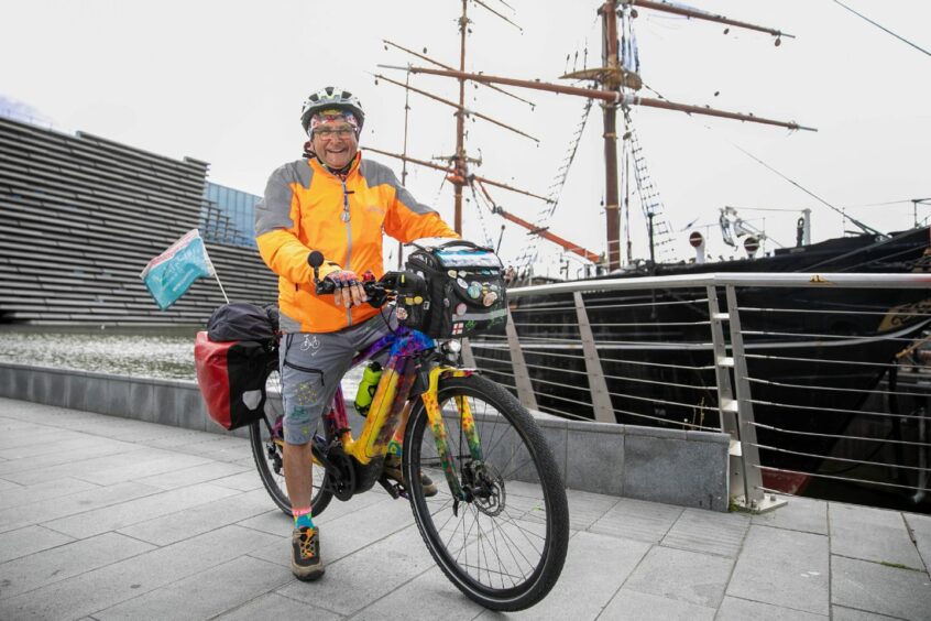 Tommy Mallet on a bicycle next to RRs Discovery.