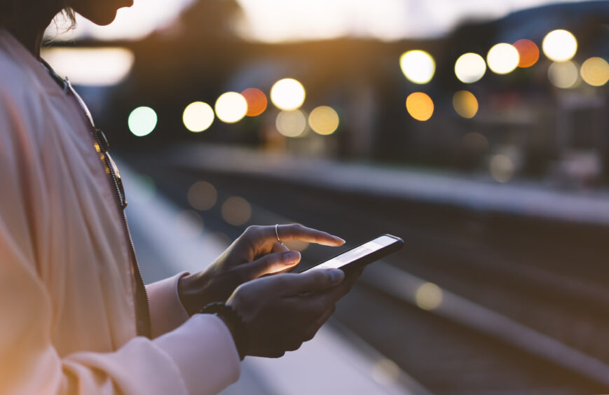 Woman using mobile phone at train station 