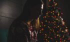 Lonely woman sitting in front of Christmas tree.