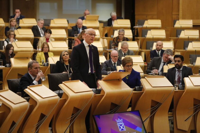 John Swinney MSP, delivering the Scottish Budget to the Scottish Parliament, watched by SNP MSPs