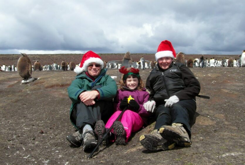 Amy as a child in the Falkland Islands with dad Anthony, mum Michele and some king penguins and chicks