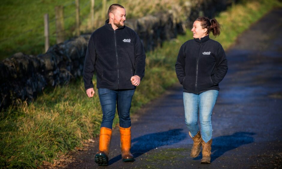 A man and a woman in Annfield Farm jackets walk down a farm track