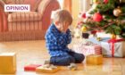 phoot shows small boy crying next to a pile of presents and a Christmas tree.