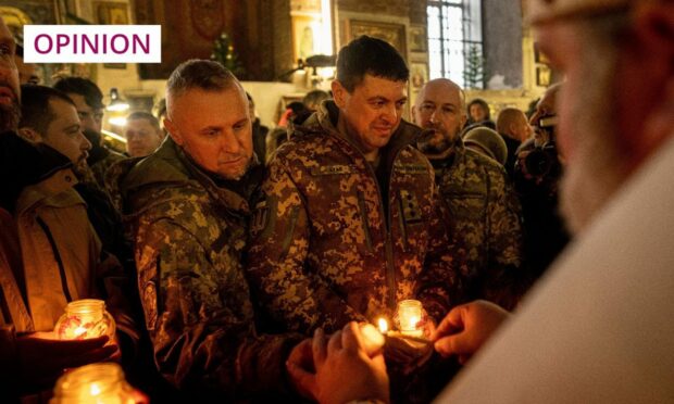 Soldiers in Ukraine receive the Bethlehem Light of Peace from a priest during a Christmas church service