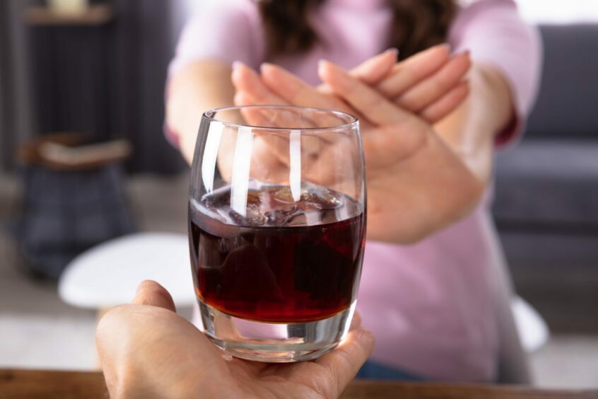 photo shows a woman's hands refusing a glass of wine.