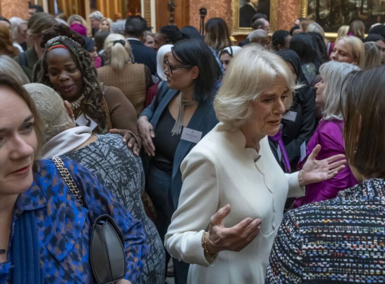 photo shows Ngozi Fulani standing behind Camilla, Queen Consort, in a crowded reception at Buckingham Palace.