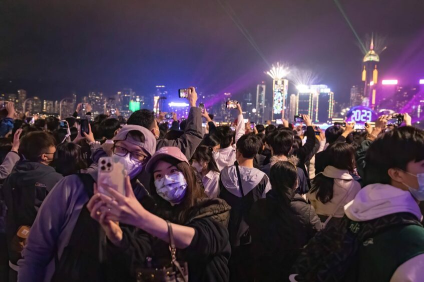 couple in covid masks posing for a selfie, as part of a large crowd celebrating the new year in Hong Kong.
