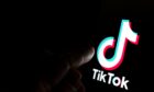 TikTok app logo on screen and a finger pointing at it.