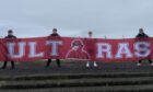 Members of Arbroath's 1880 Crew display their banner at Gayfield. Image: Arbroath FC.