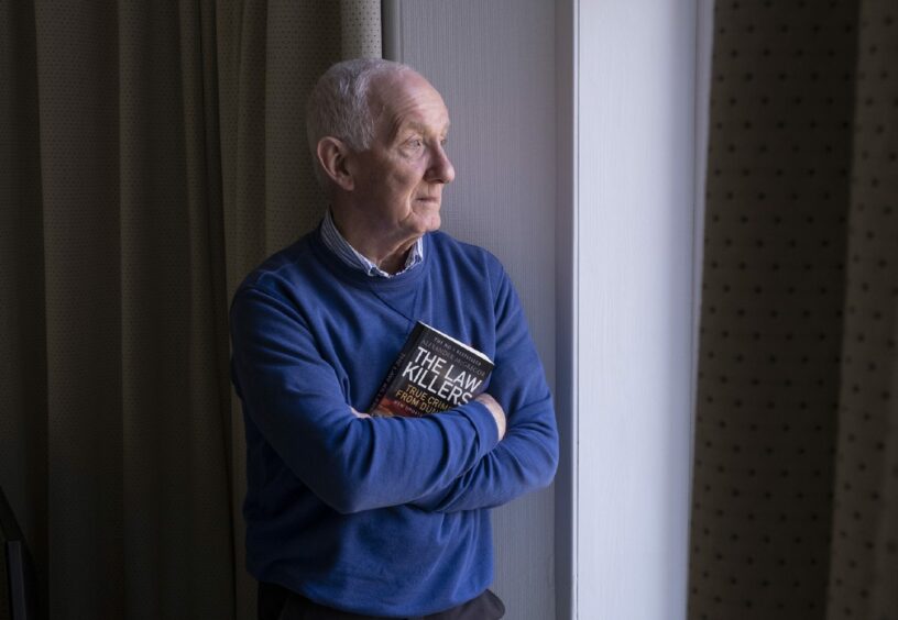 Law Killers author Alexander McGregor holding a copy of his book.