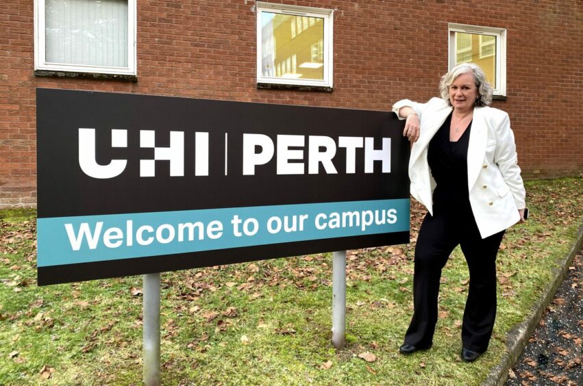 Margaret Cook standing next to sign which reads 'UHI Perth: welcome to our campus'