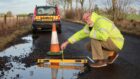 Mark Hooghiemstra next to a two-metre pothole on the C44 road between Letham and Brechin. Image: Mark Hooghiemstra.