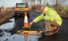 Mark Hooghiemstra next to a two-metre pothole on the C44 road between Letham and Brechin. Image: Mark Hooghiemstra.