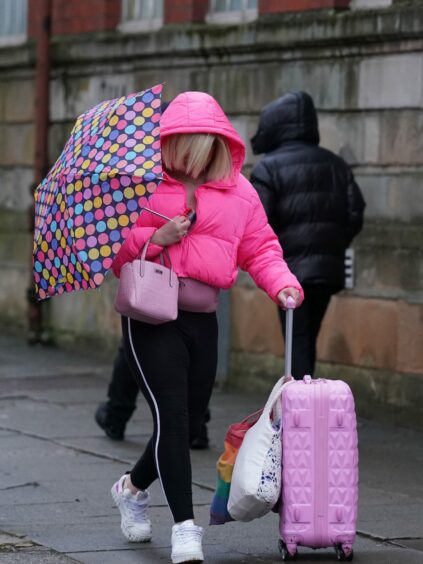 transgender rapist Isla Bryson walking to court in pink anorak with pink suitcase and umbrella