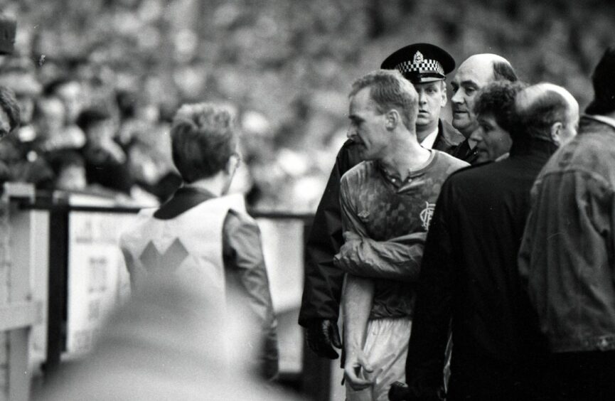 A furious John Brown is escorted off the field after his red card. Image: DC Thomson.