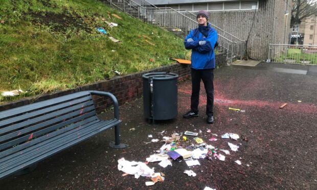 Euan Haines beside rubbish left on a communal pathway  near Hilltown Court. Image: James Simpson/DC Thomson