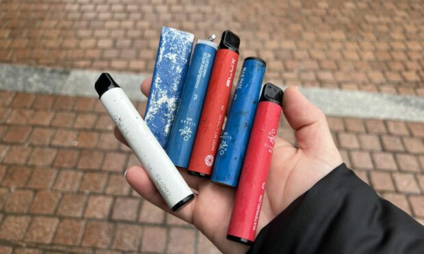 Hand holding disposable vapes.