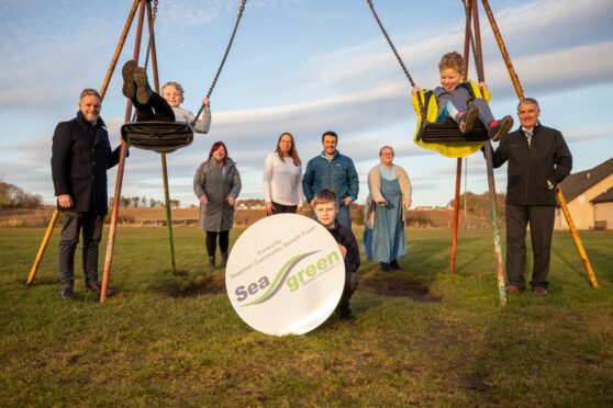 Youngsters Owen Millar, 7, Russell Simpson, 10, and Ben Simpson, 5, celebrate the Seagreen boost with community and windfarm figures at the park. Image: Kim Cessford/DC Thomson